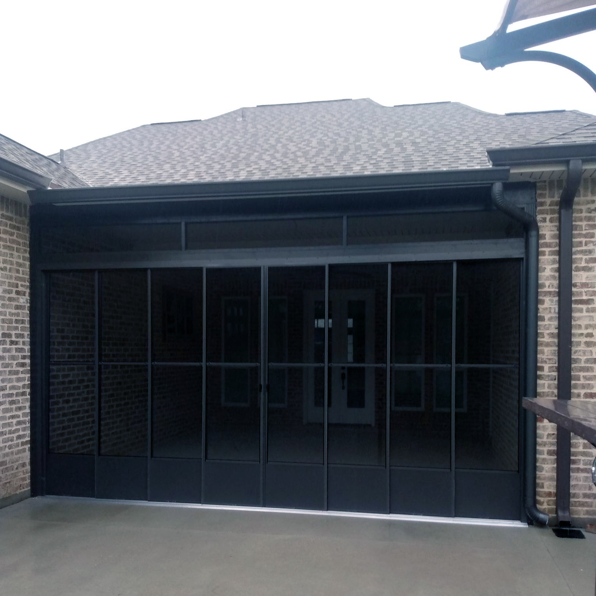 A screened in porch with a brick building in the background.