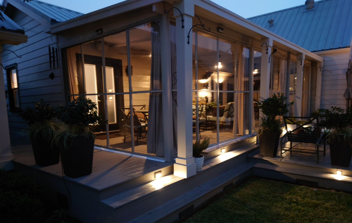 A screened in porch is lit up at night.