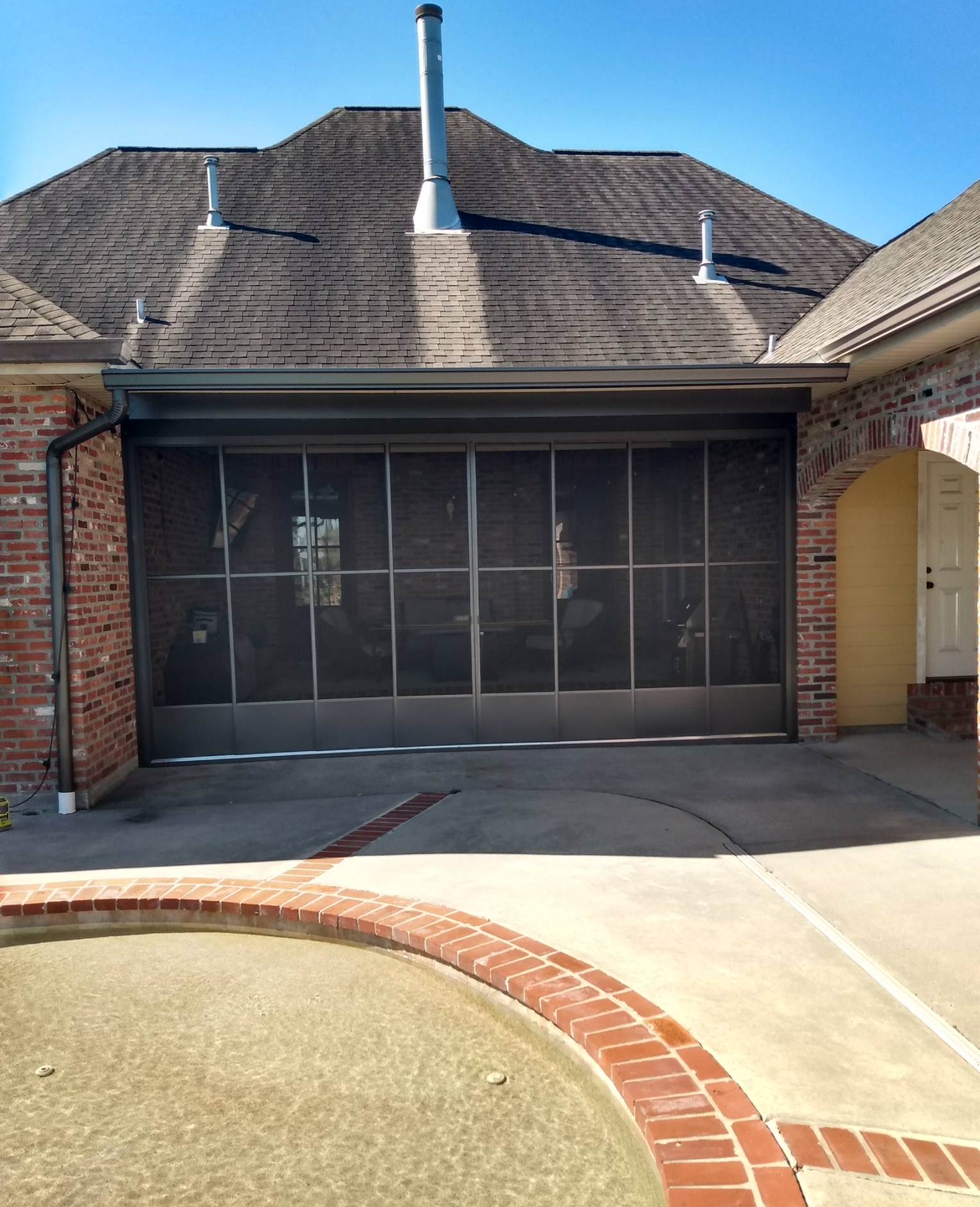 A brick house with a screened in garage door.