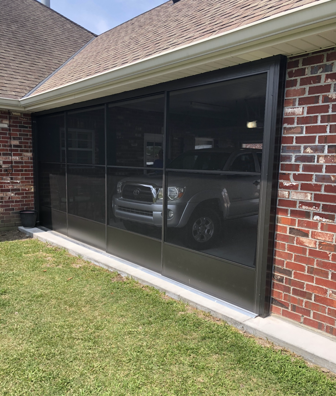 A truck is parked in front of a screened in porch.