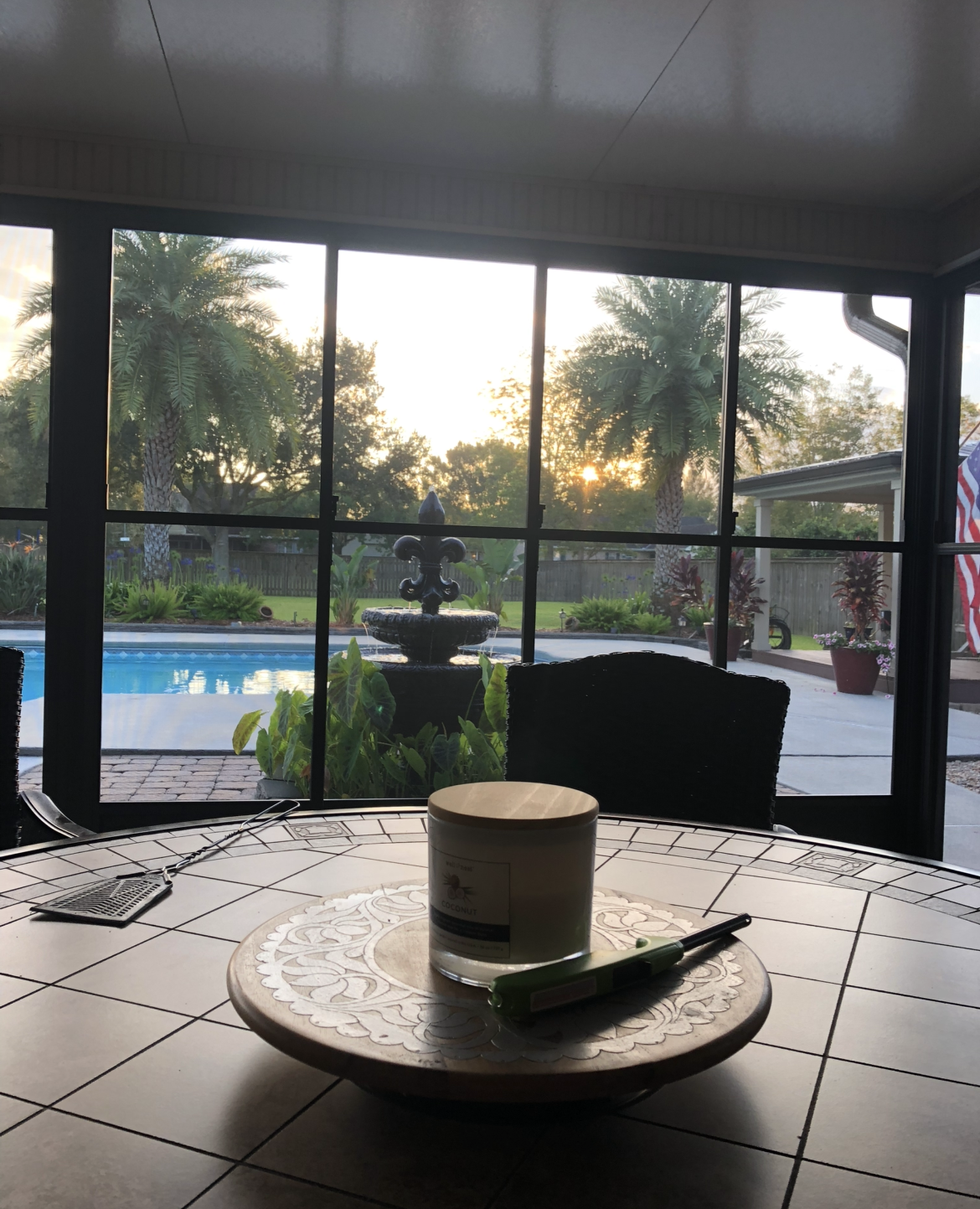 A table with a candle on it and a view of a pool.