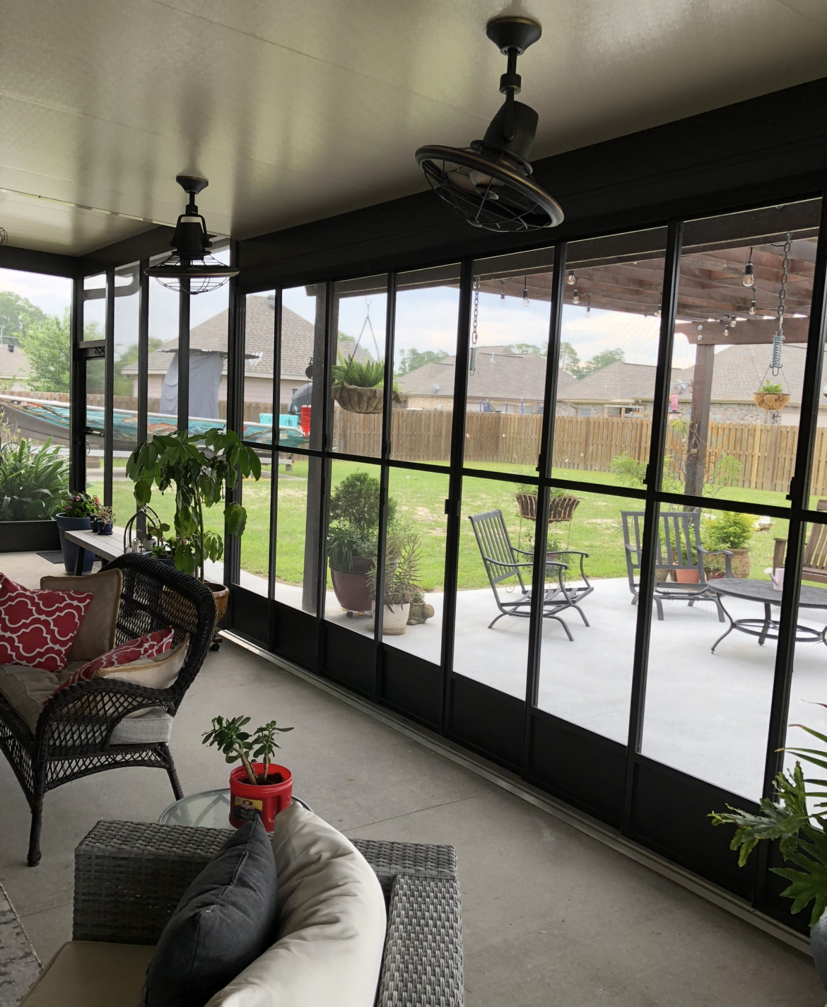 A screened in porch with a lot of windows and a ceiling fan.