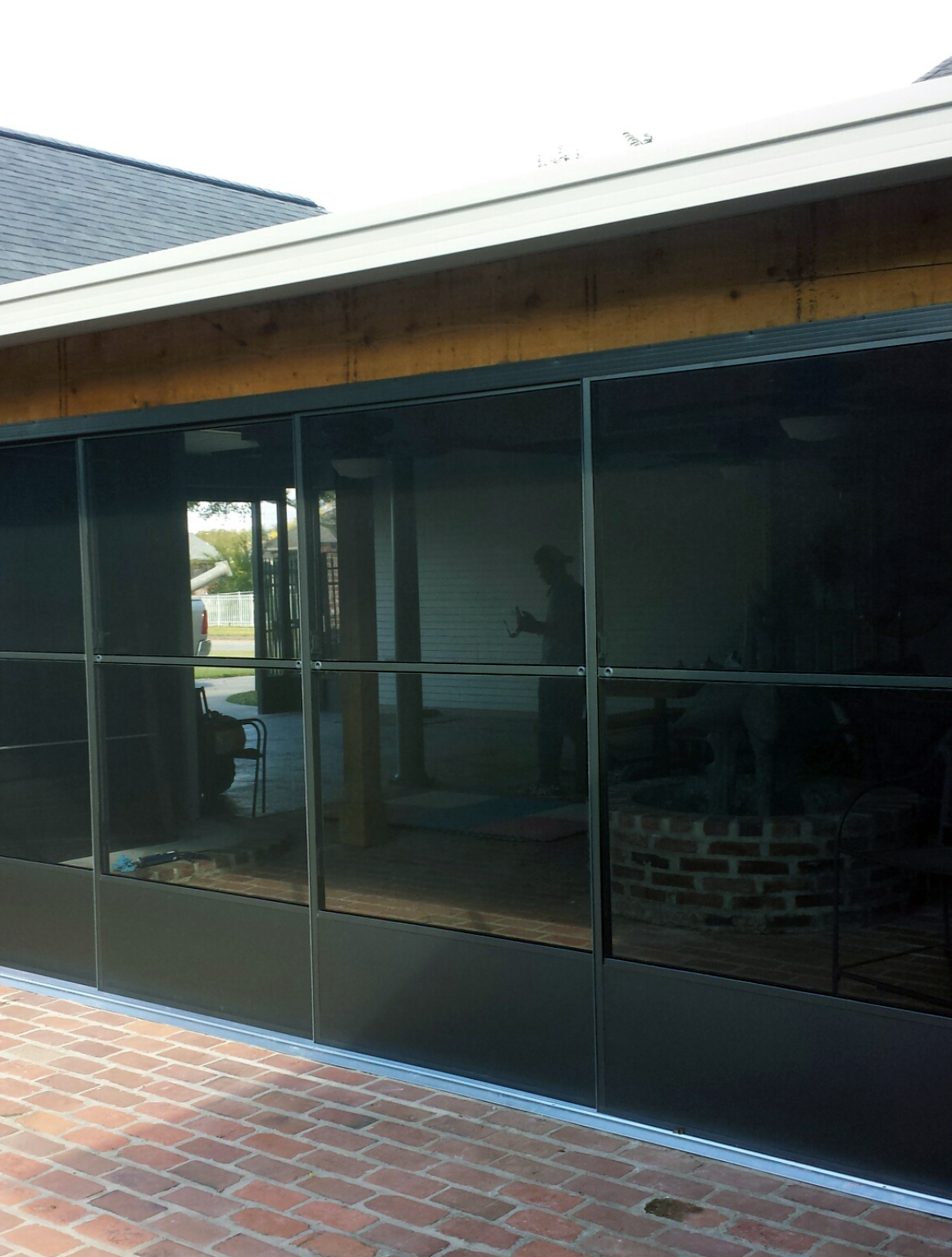 A screened in porch with a lot of windows and a brick floor.