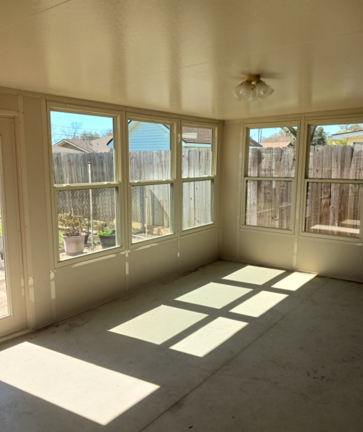 A room with a lot of windows and a fence in the background.