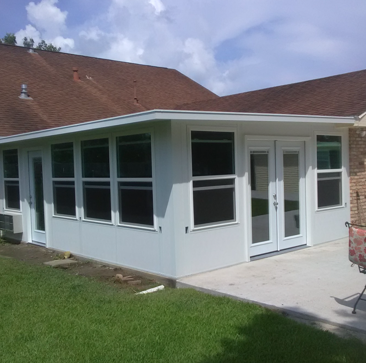A white house with a brown roof and many windows.