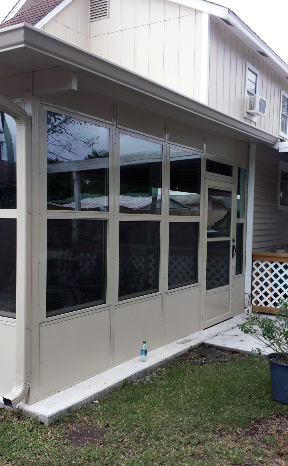 A screened in porch with a lot of windows on the side of a house.