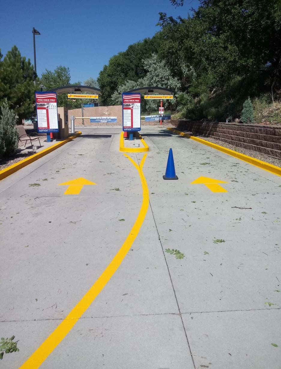 A parking lot with yellow arrows and blue cones