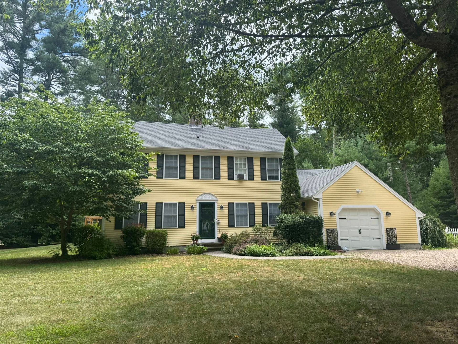 Yellow two-story house with black shutters, attached garage, and green lawn.