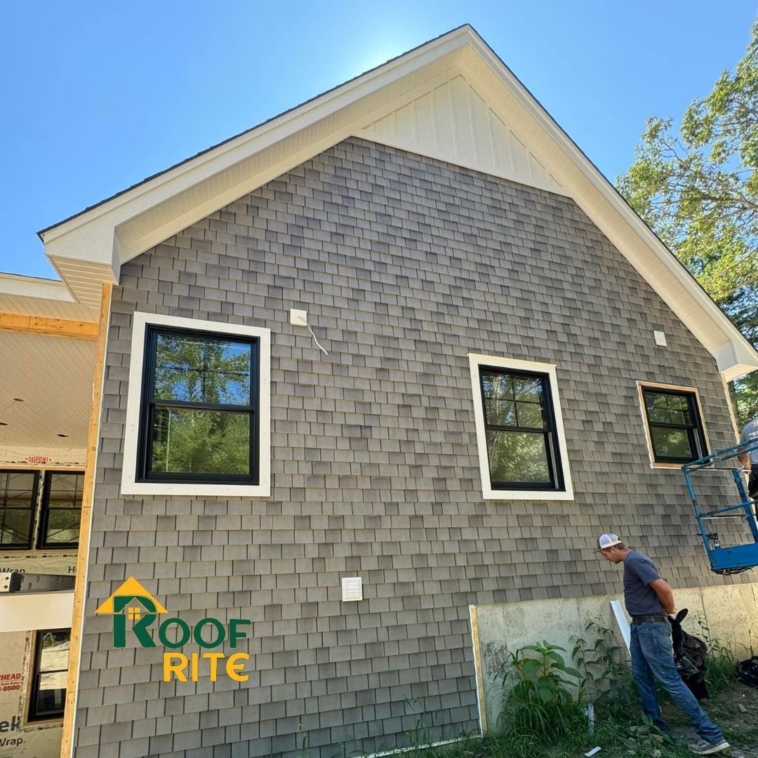 House with gray shingle siding, black windows, a worker, and 