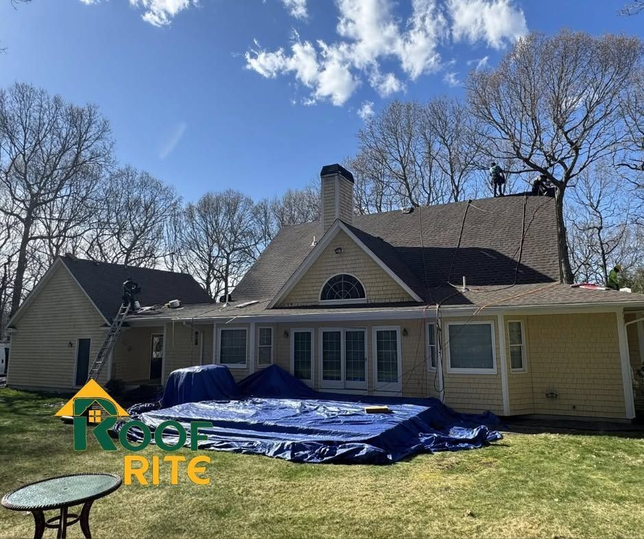House exterior with roof repair materials spread across the front yard under a blue sky.