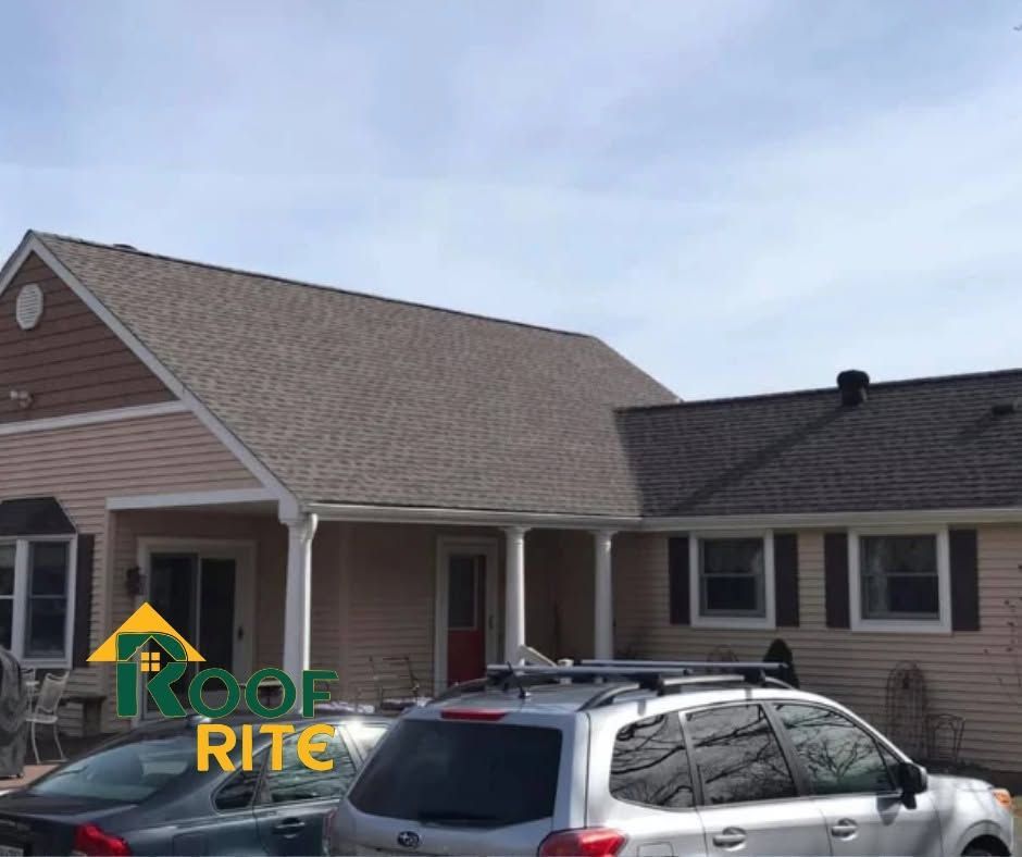 Suburban house with tan siding and brown roof, parked SUV in front