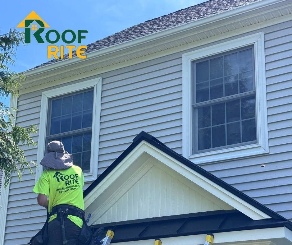 Roof Rite worker inspecting a white house exterior under a gable roof