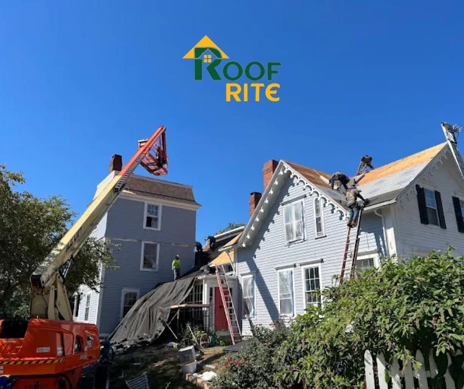 Workers on a roof beside two houses and a lifted crane boom