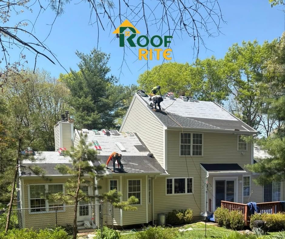 Roof Rite crew repairing a light green house roof under a clear blue sky.