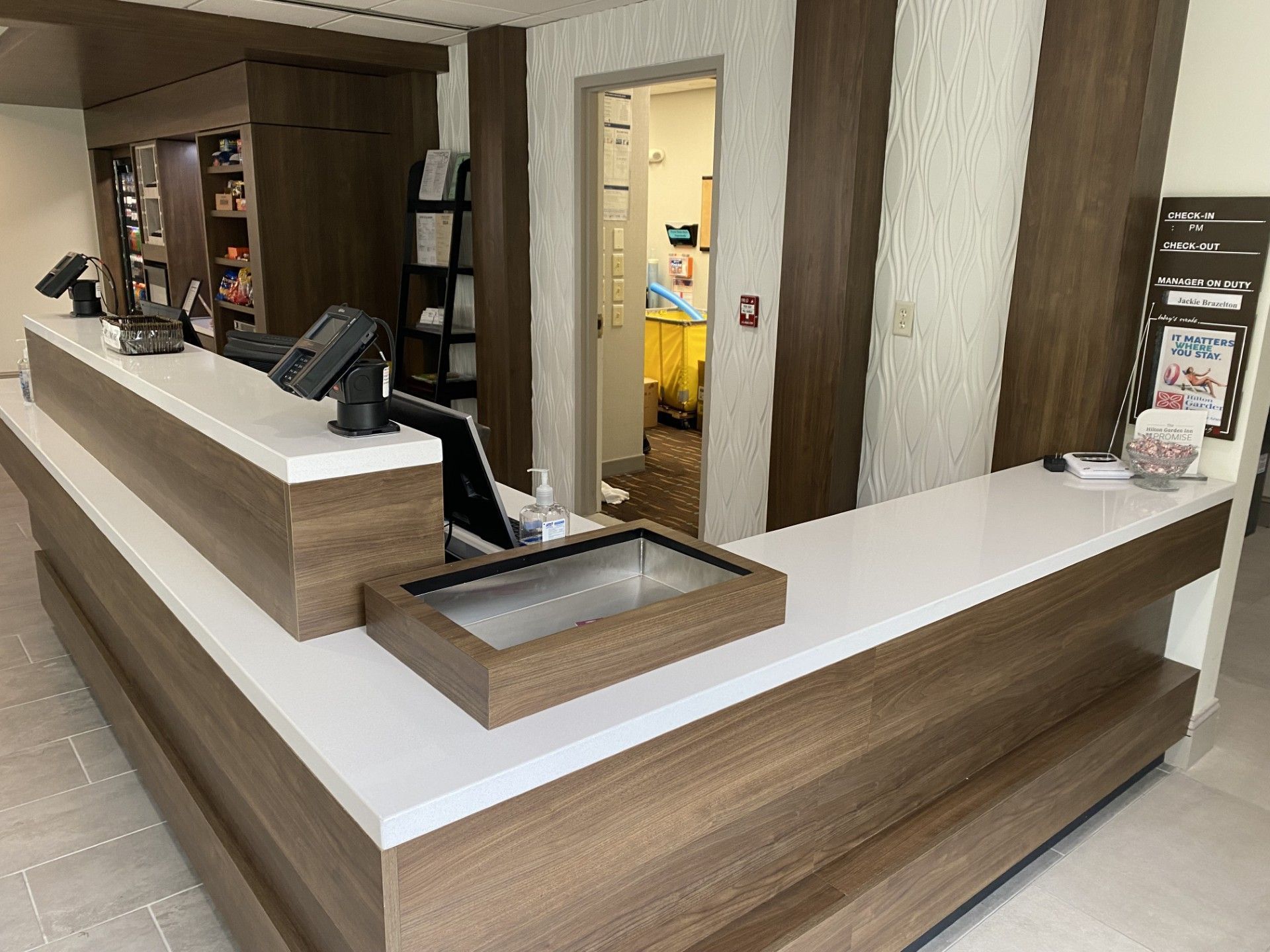 A hotel lobby with a long wooden counter and a white counter top.