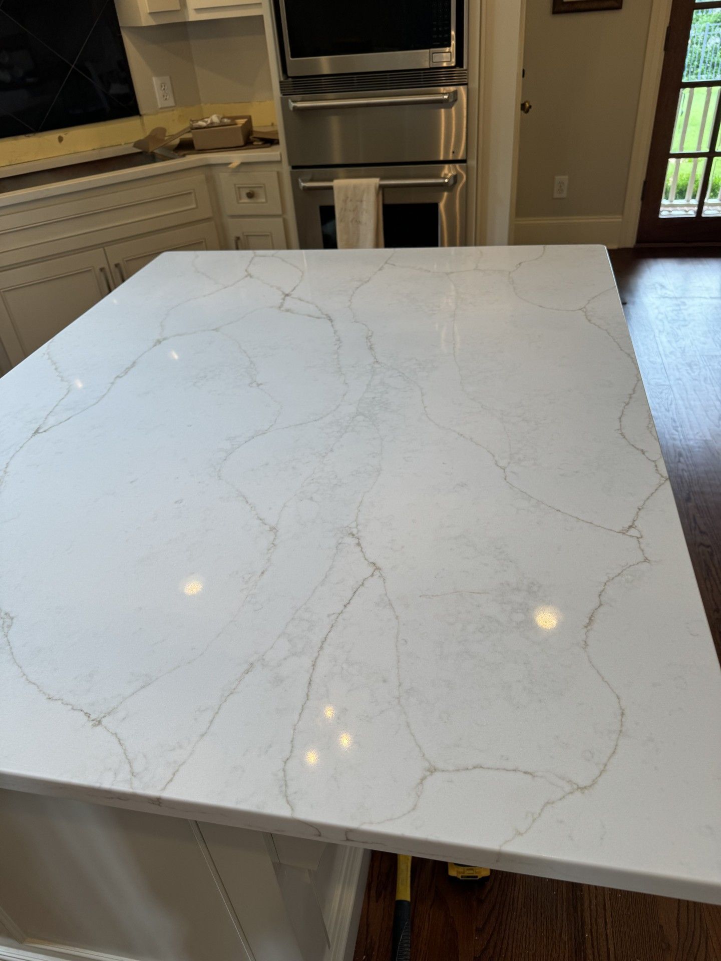 A white marble counter top in a kitchen with a stainless steel oven.
