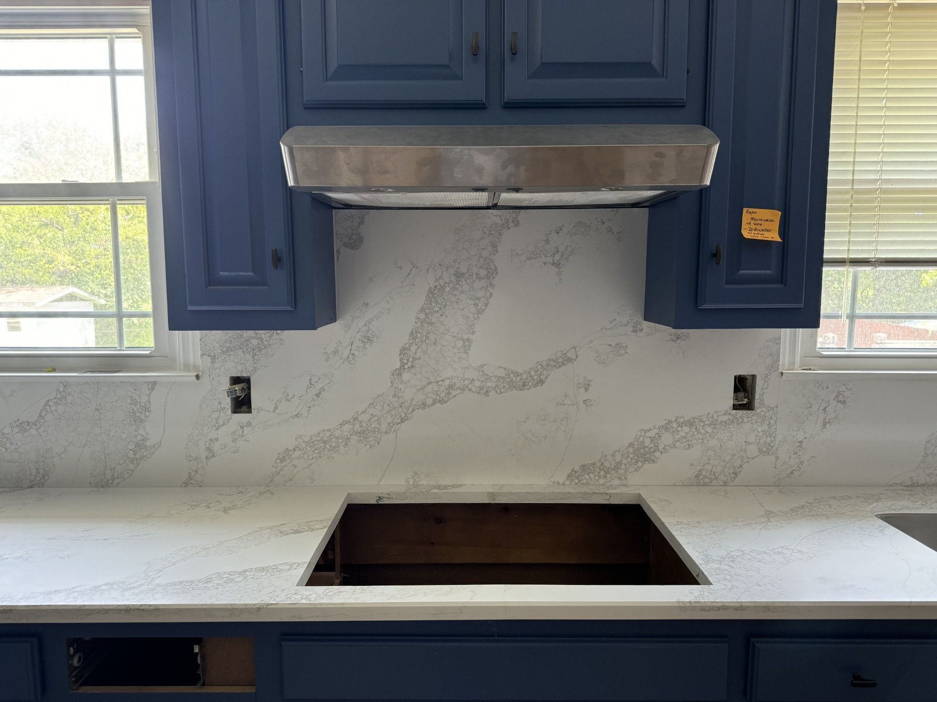 A kitchen with blue cabinets , white counter tops , and a copper stove top oven.