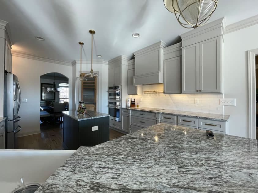 A kitchen with gray cabinets and granite counter tops.