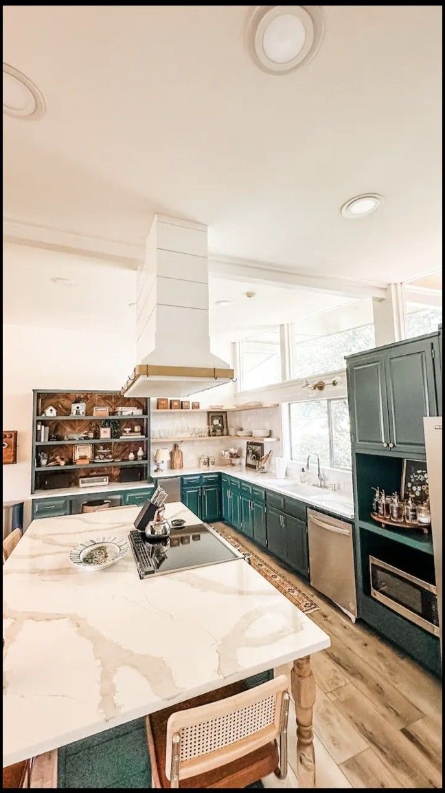 A kitchen with blue cabinets , white counter tops , and a large island.