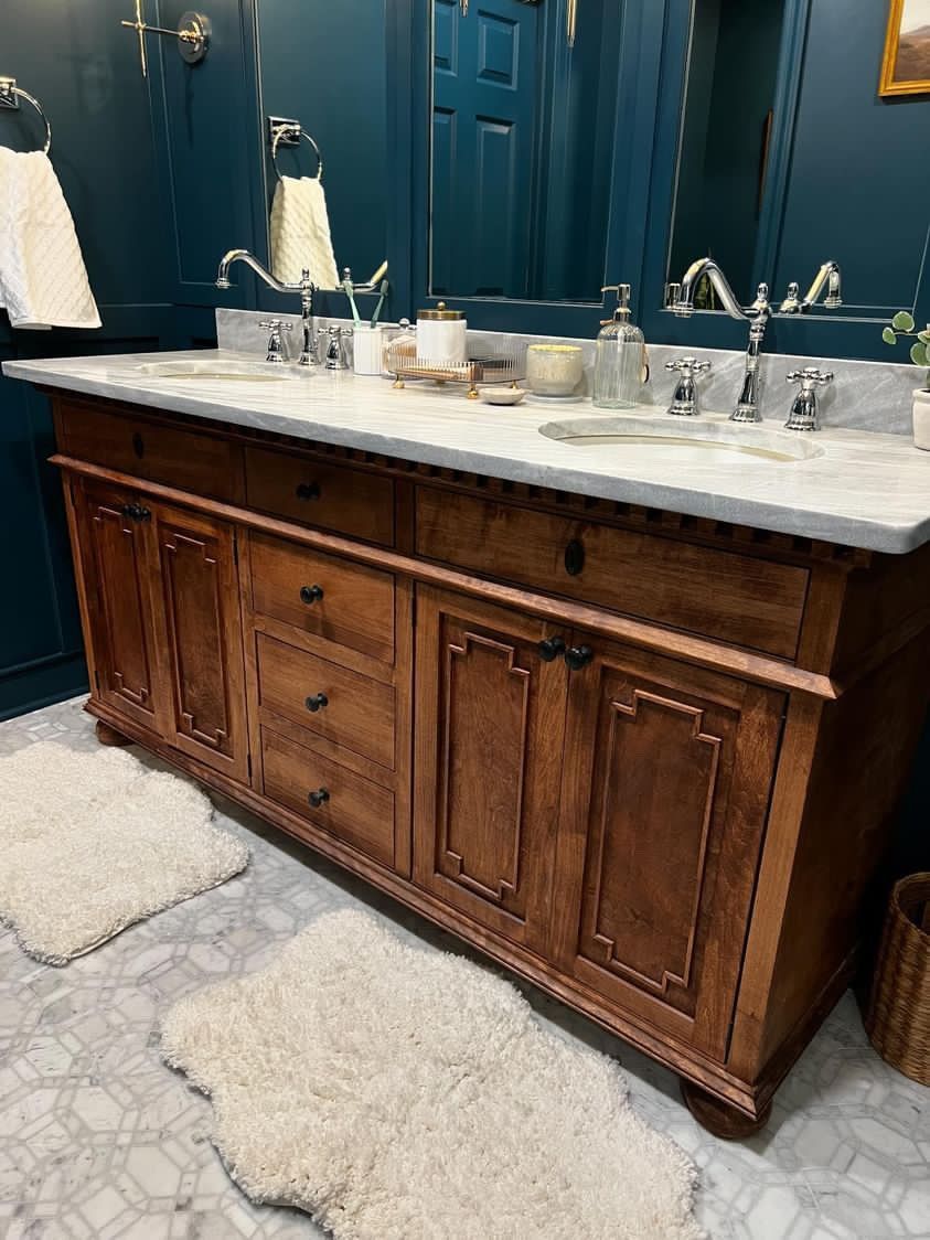 A bathroom with two sinks , a mirror , and a wooden vanity.