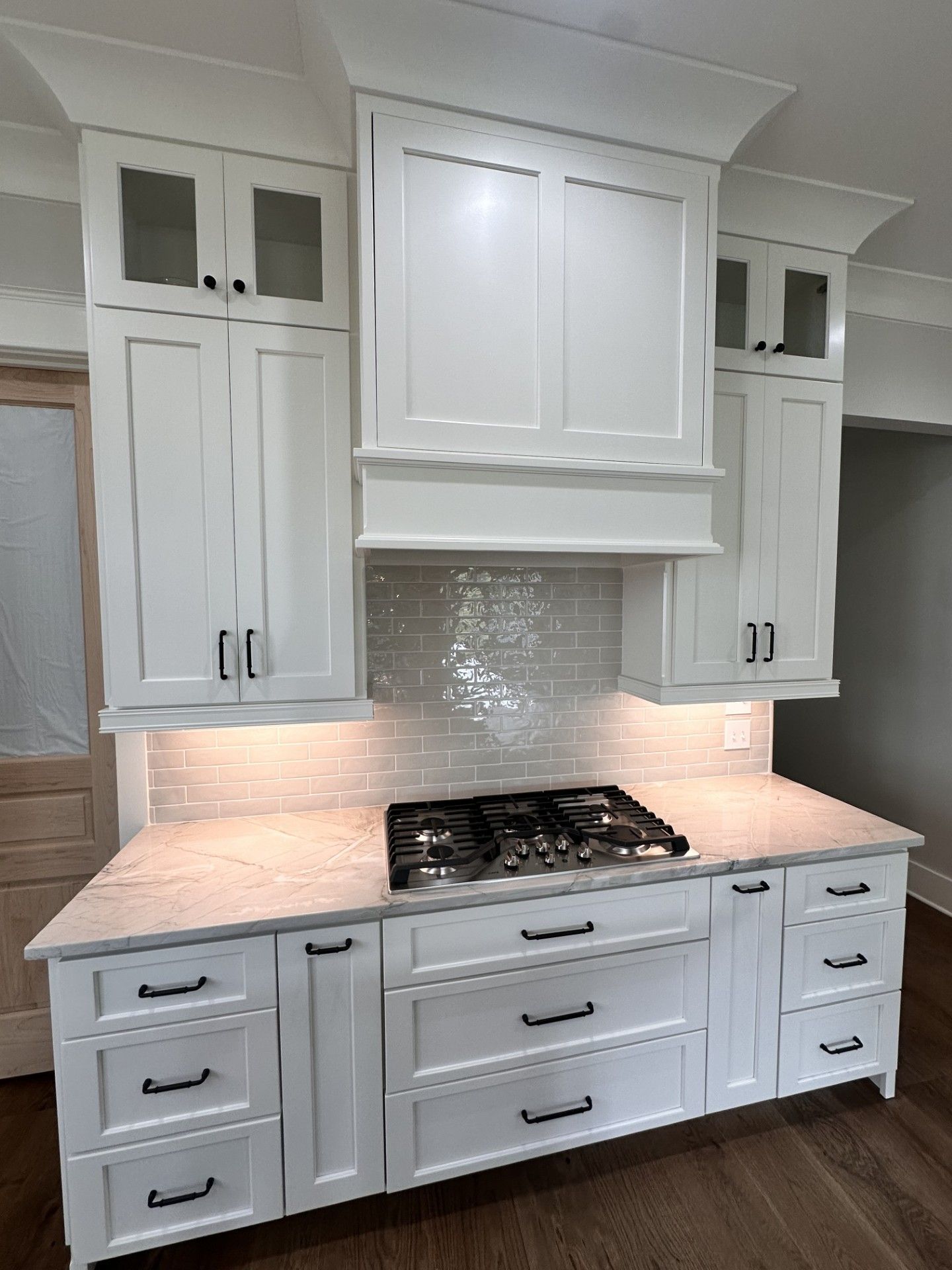 A kitchen with white cabinets and a stove top oven.