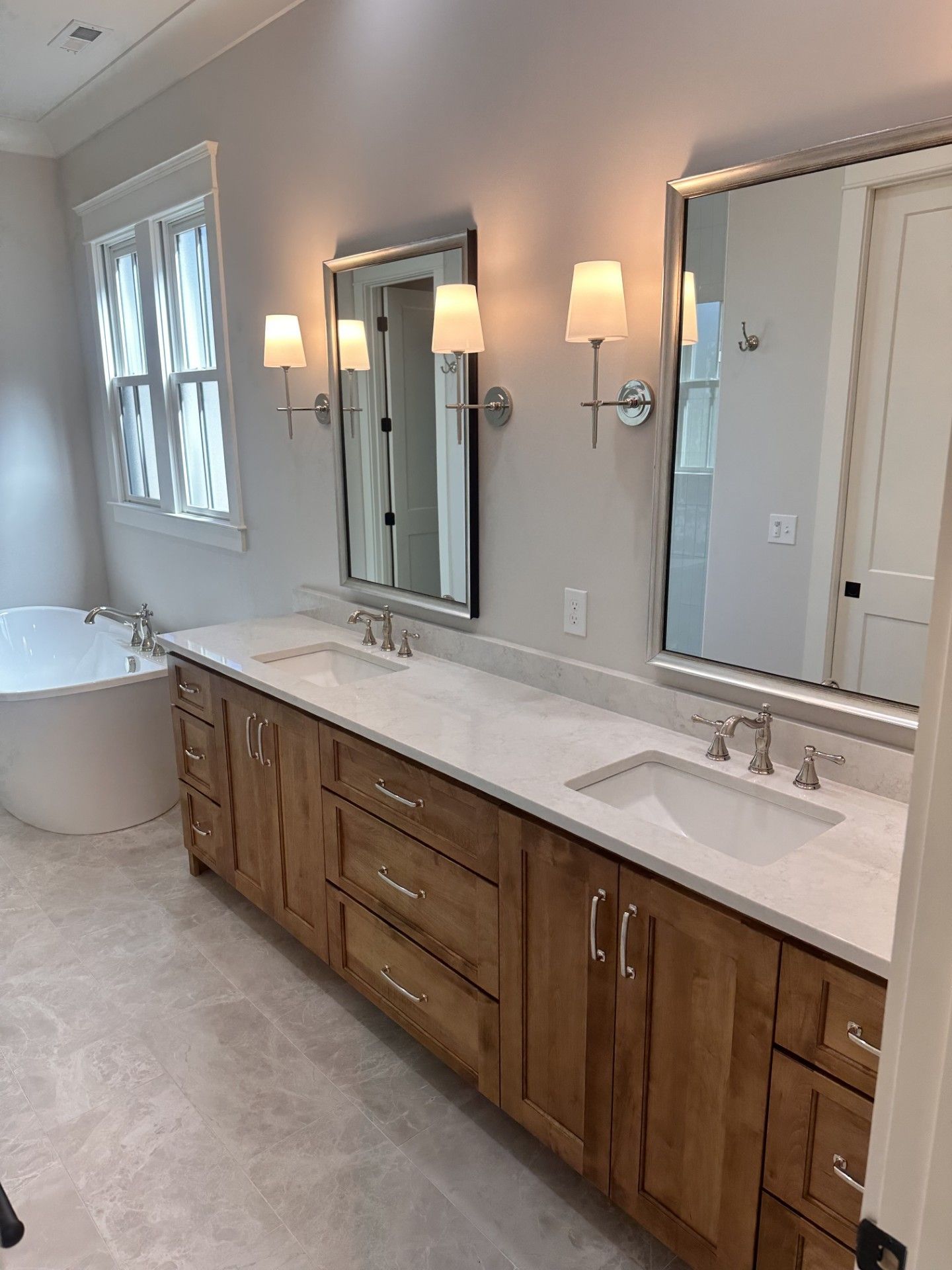 A bathroom with two sinks , two mirrors and a bathtub.