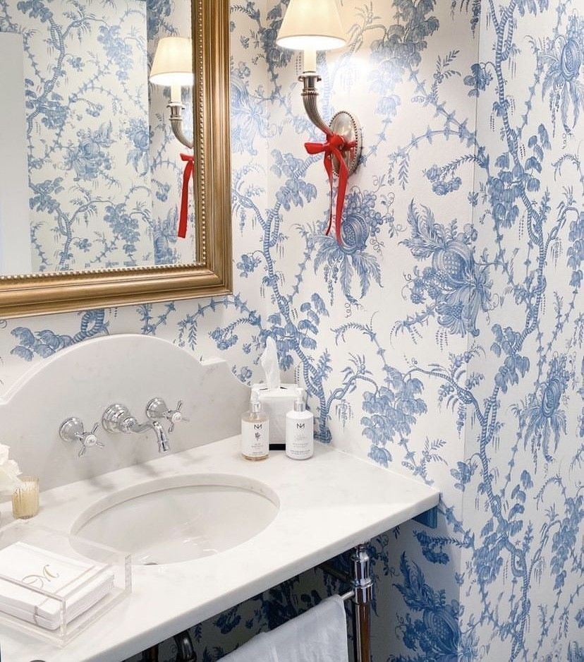 A bathroom with blue and white floral wallpaper and a sink