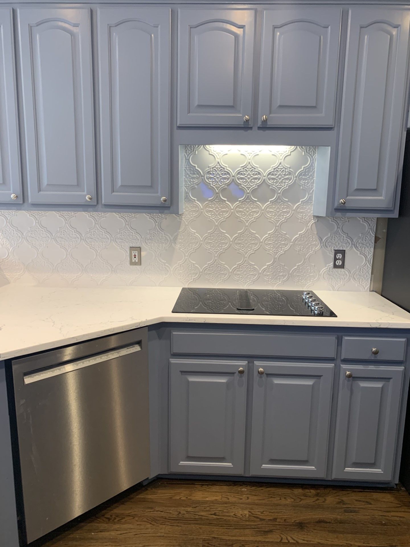 A kitchen with gray cabinets and a stainless steel dishwasher.