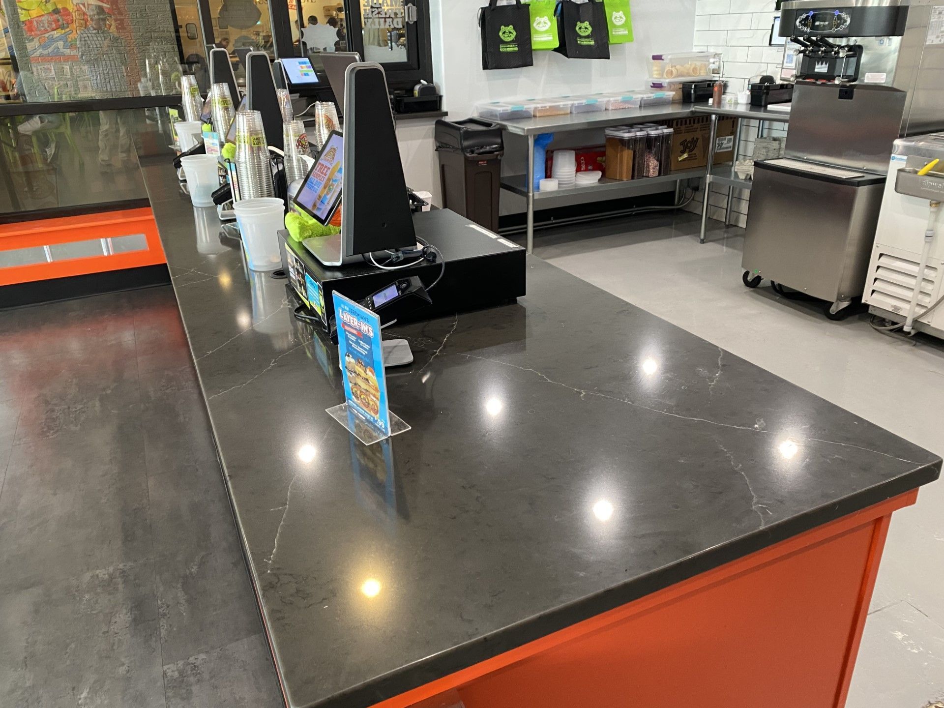 A long counter in a restaurant with a computer on it.