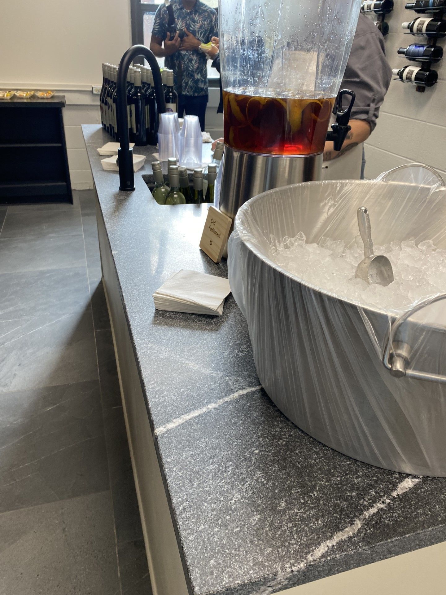 A counter with a bowl of ice and a pitcher of liquid on it.