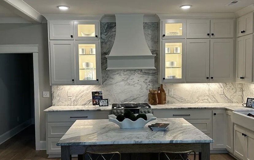 A kitchen with white cabinets , granite counter tops , and a large island.