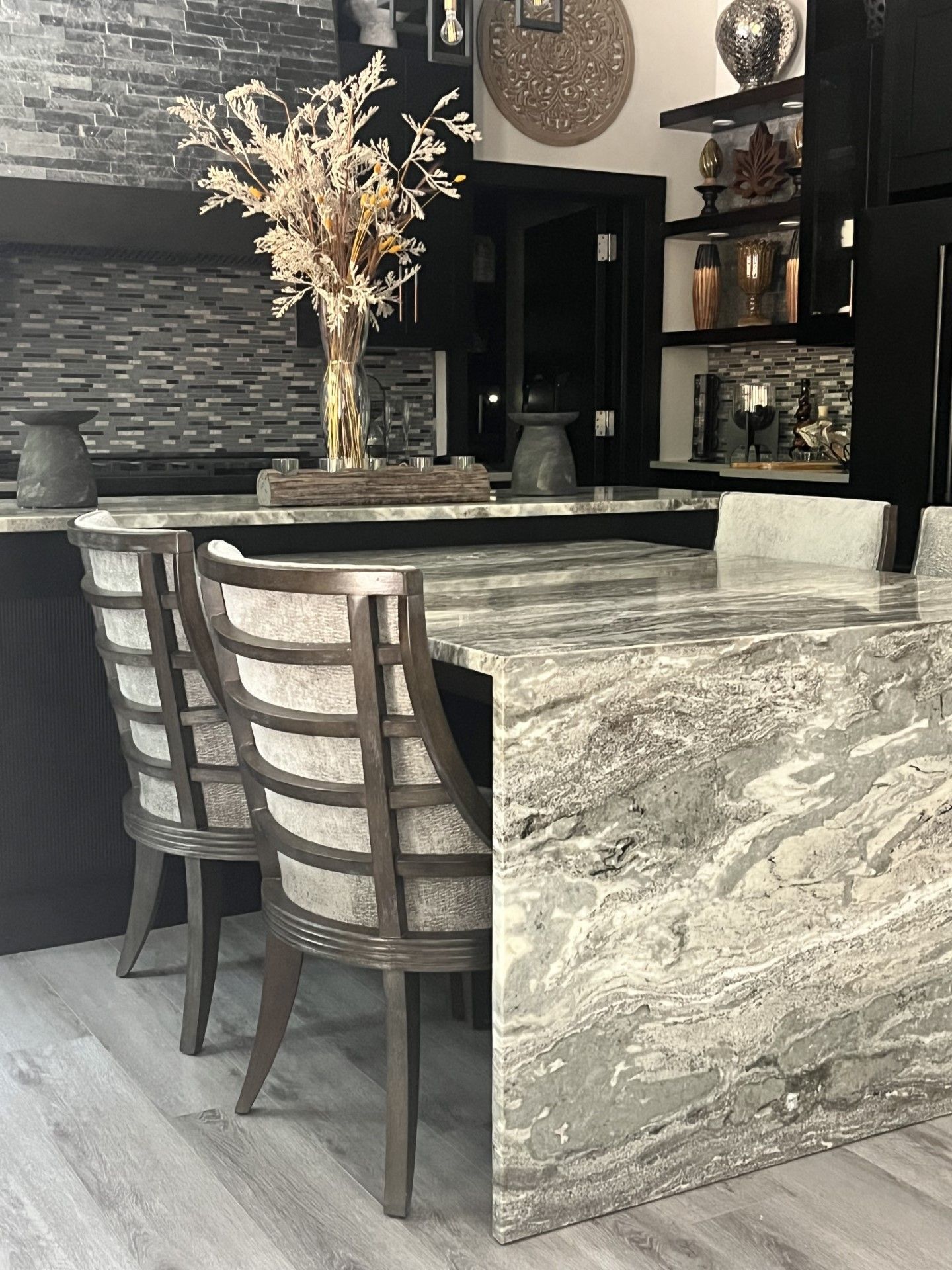 A kitchen with a marble counter top and chairs.