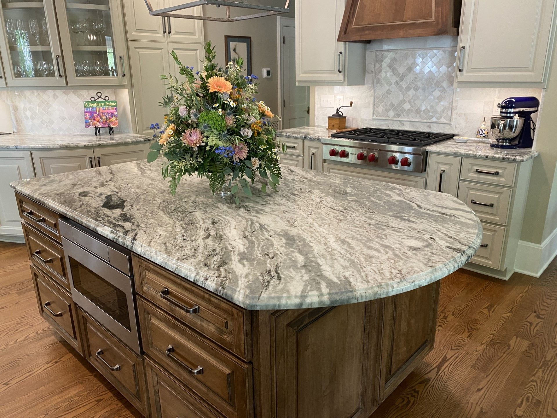 A kitchen with a large island and a vase of flowers on top of it.