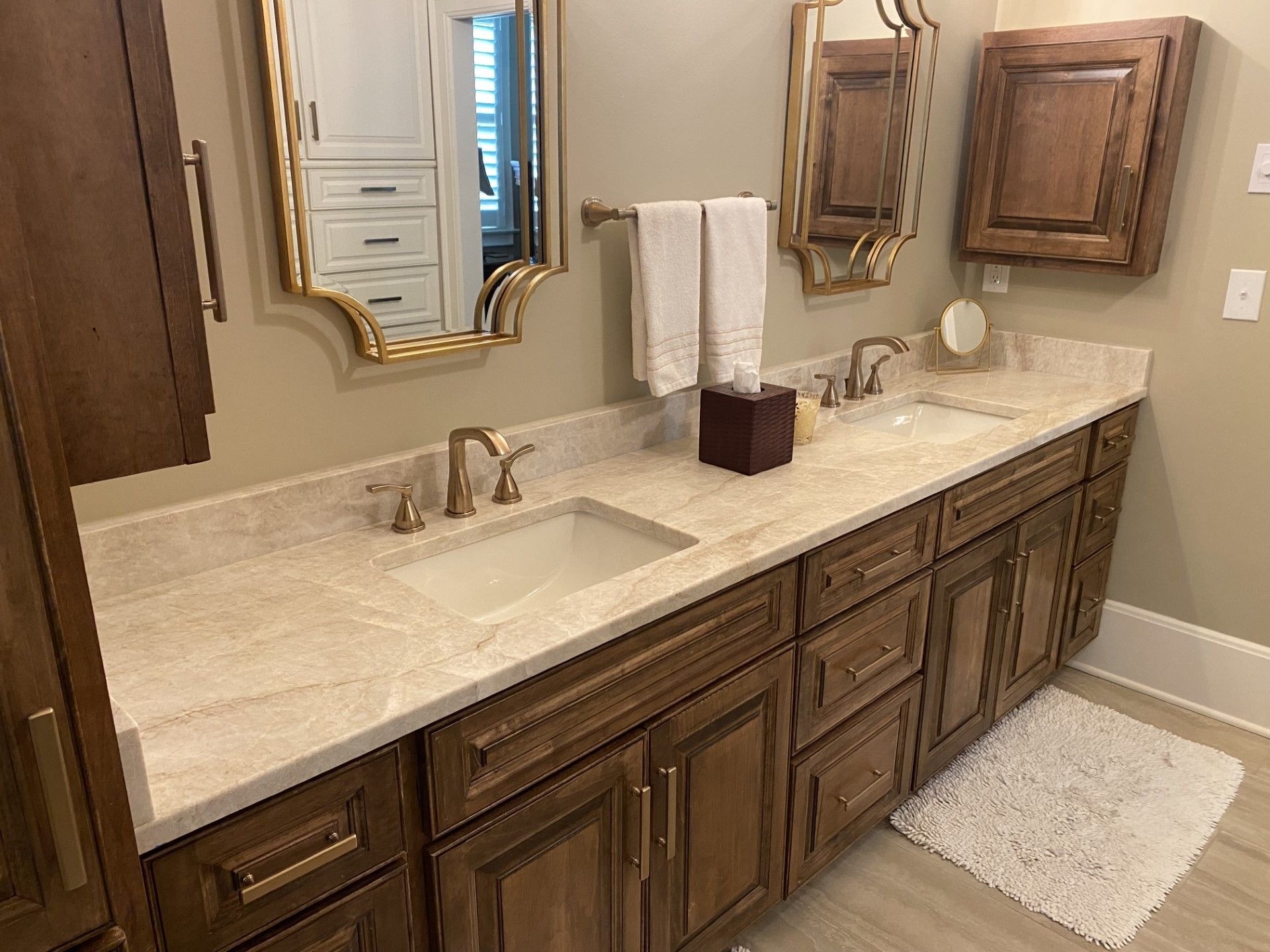 A bathroom with two sinks , two mirrors , and wooden cabinets.