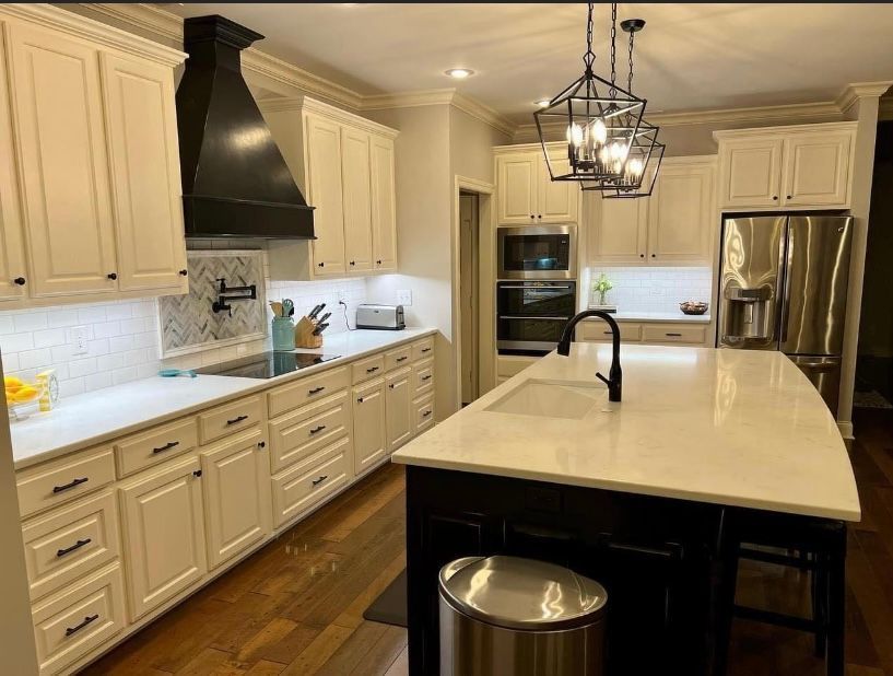 A kitchen with white cabinets , stainless steel appliances , and a large island.