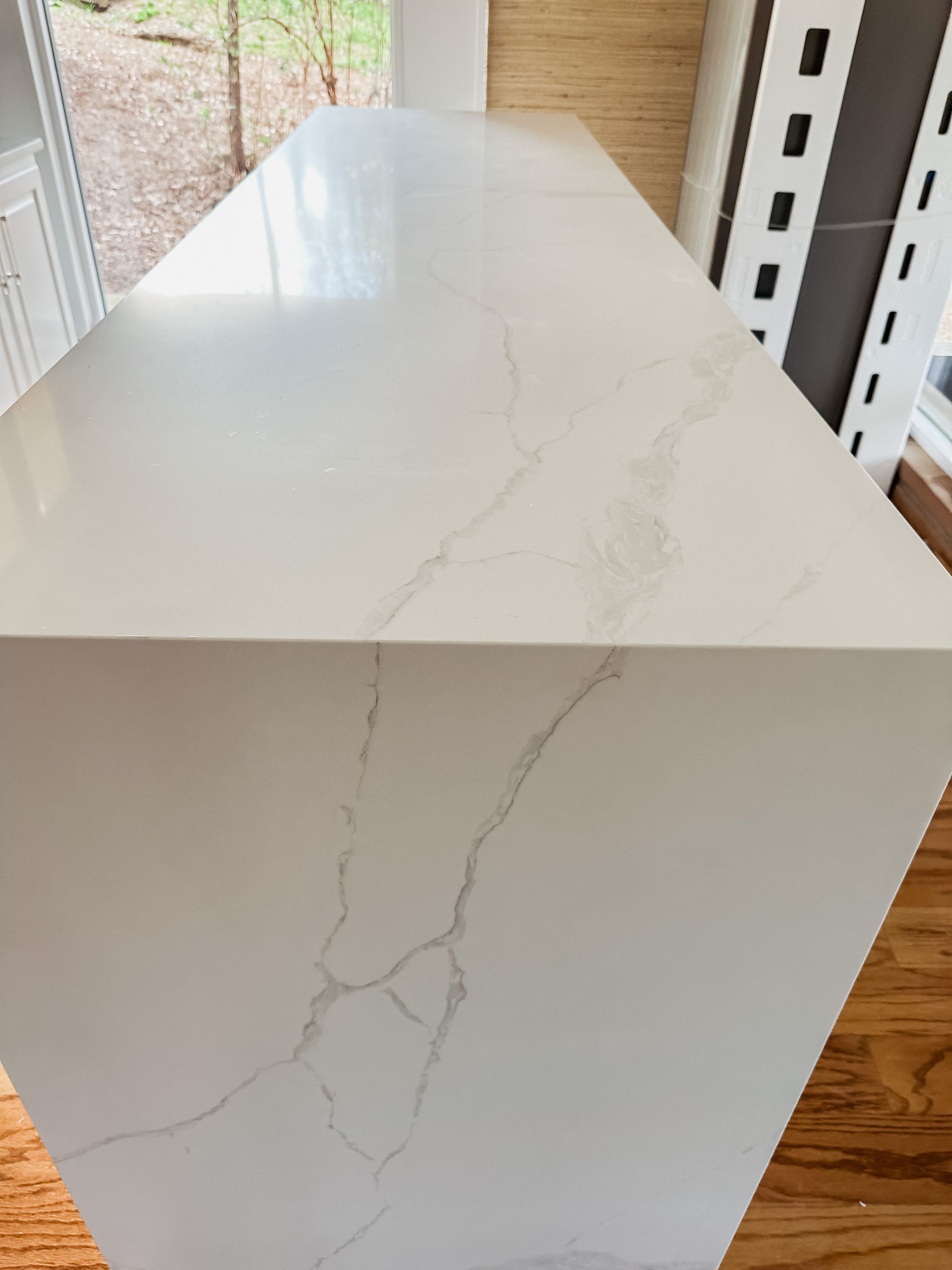 A white counter top is sitting on a wooden floor in a kitchen.