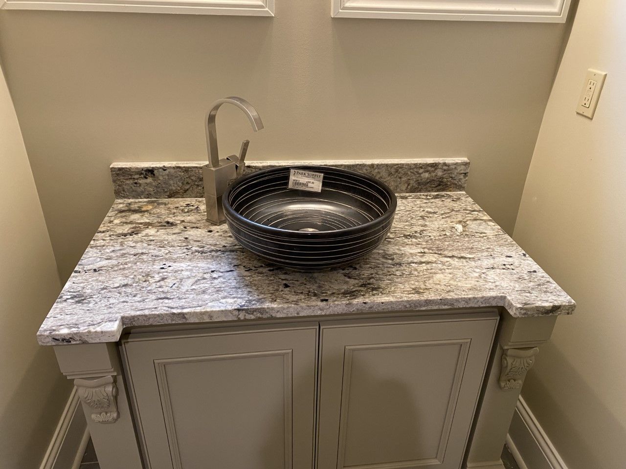 A bathroom sink is sitting on top of a granite counter top.