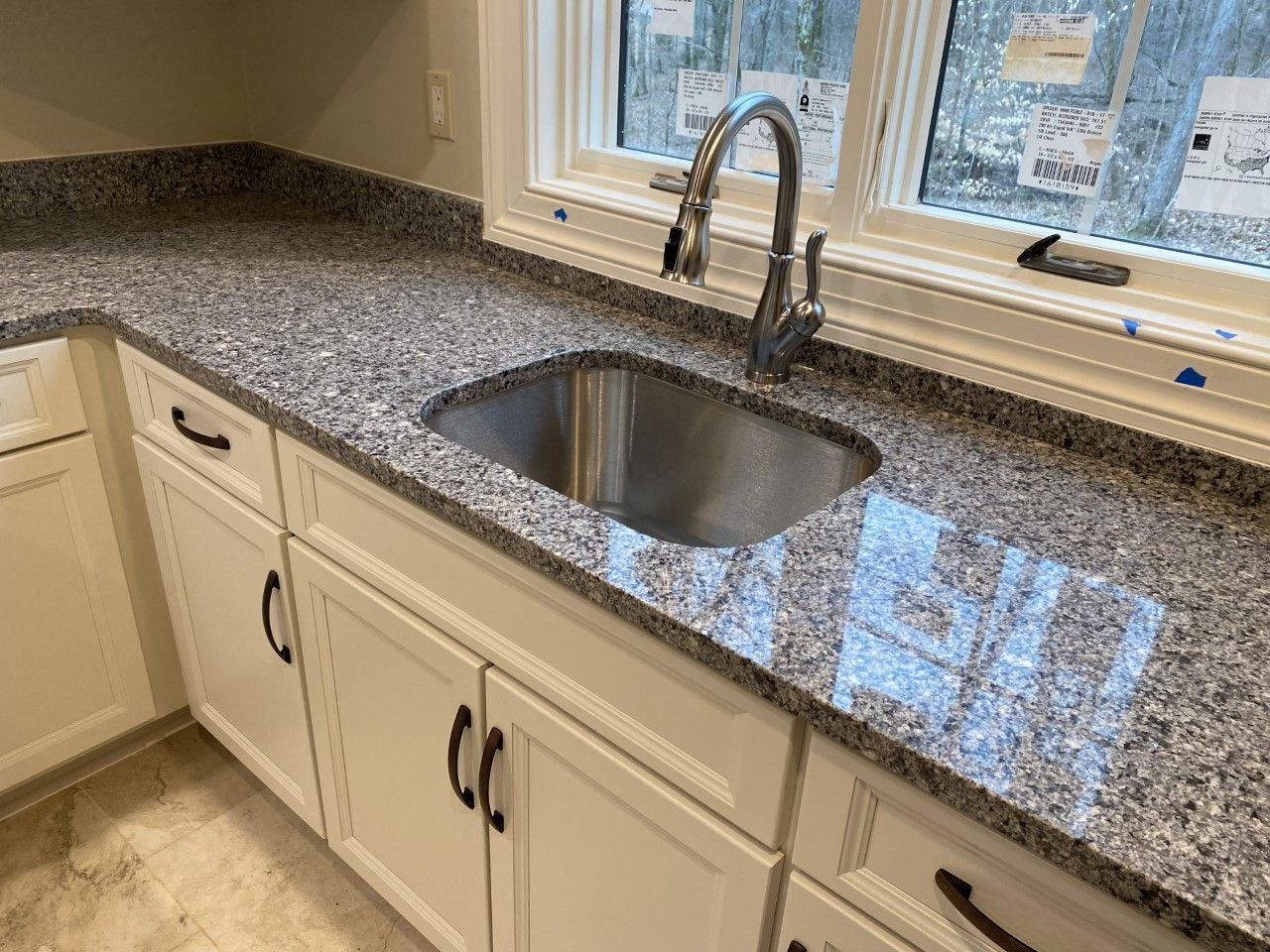 A kitchen with a stainless steel sink and granite counter tops.