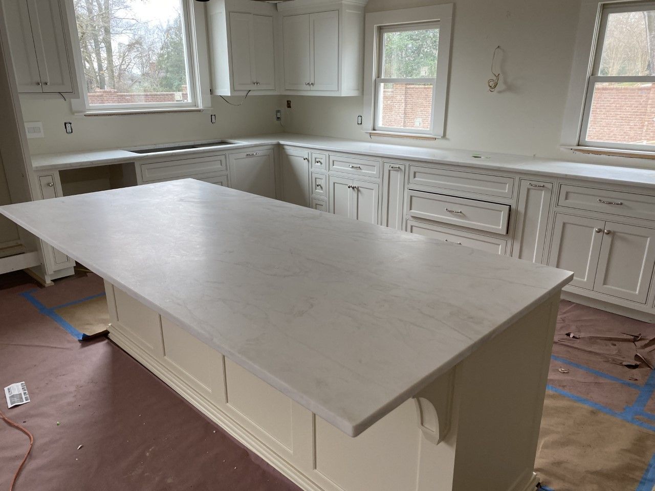 A kitchen with white cabinets and a large island in the middle.