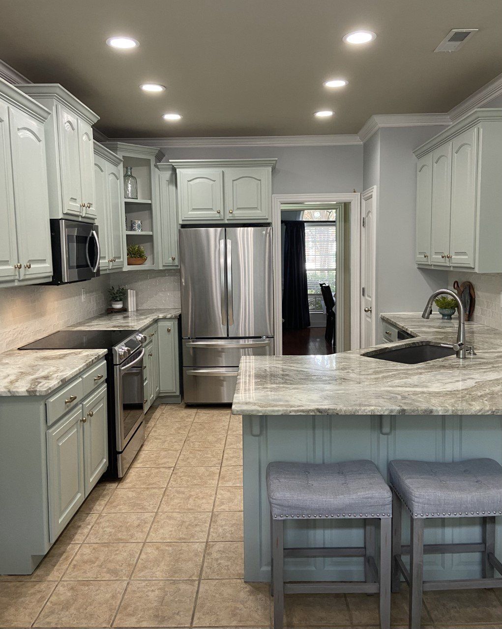 A kitchen with stainless steel appliances , granite counter tops , and white cabinets.
