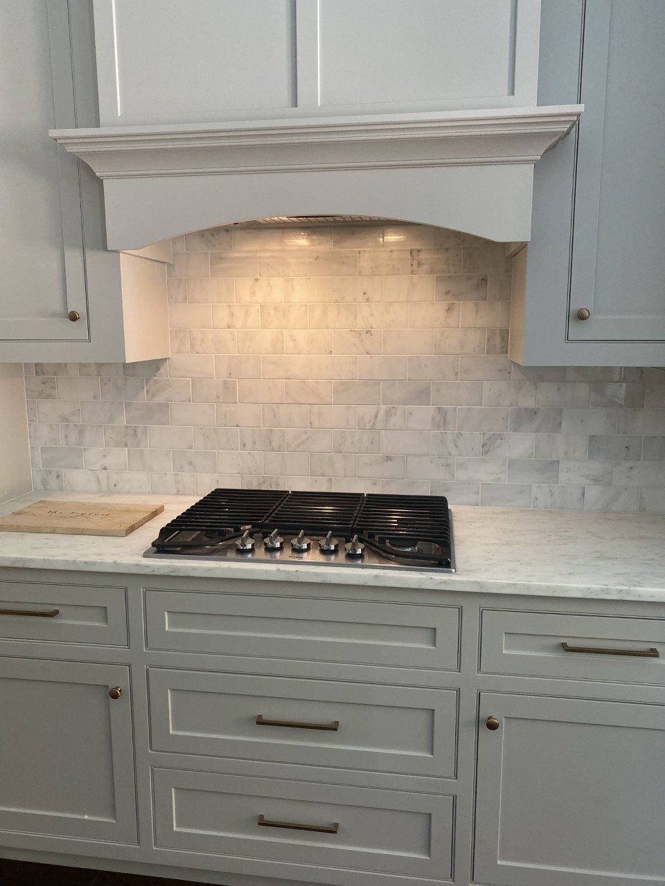 A kitchen with white cabinets and a stove top oven