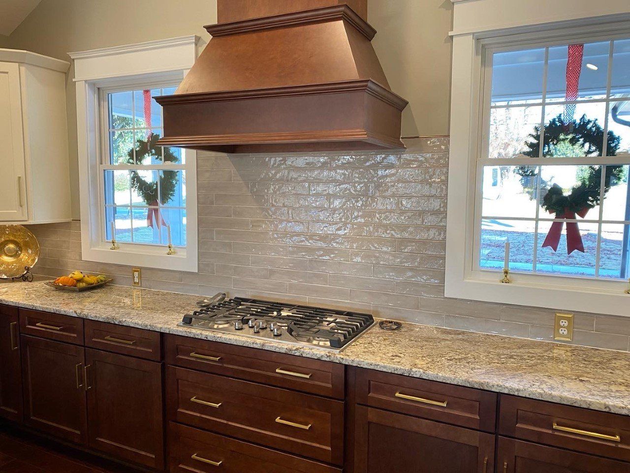 A kitchen with a stove top oven and a copper hood.