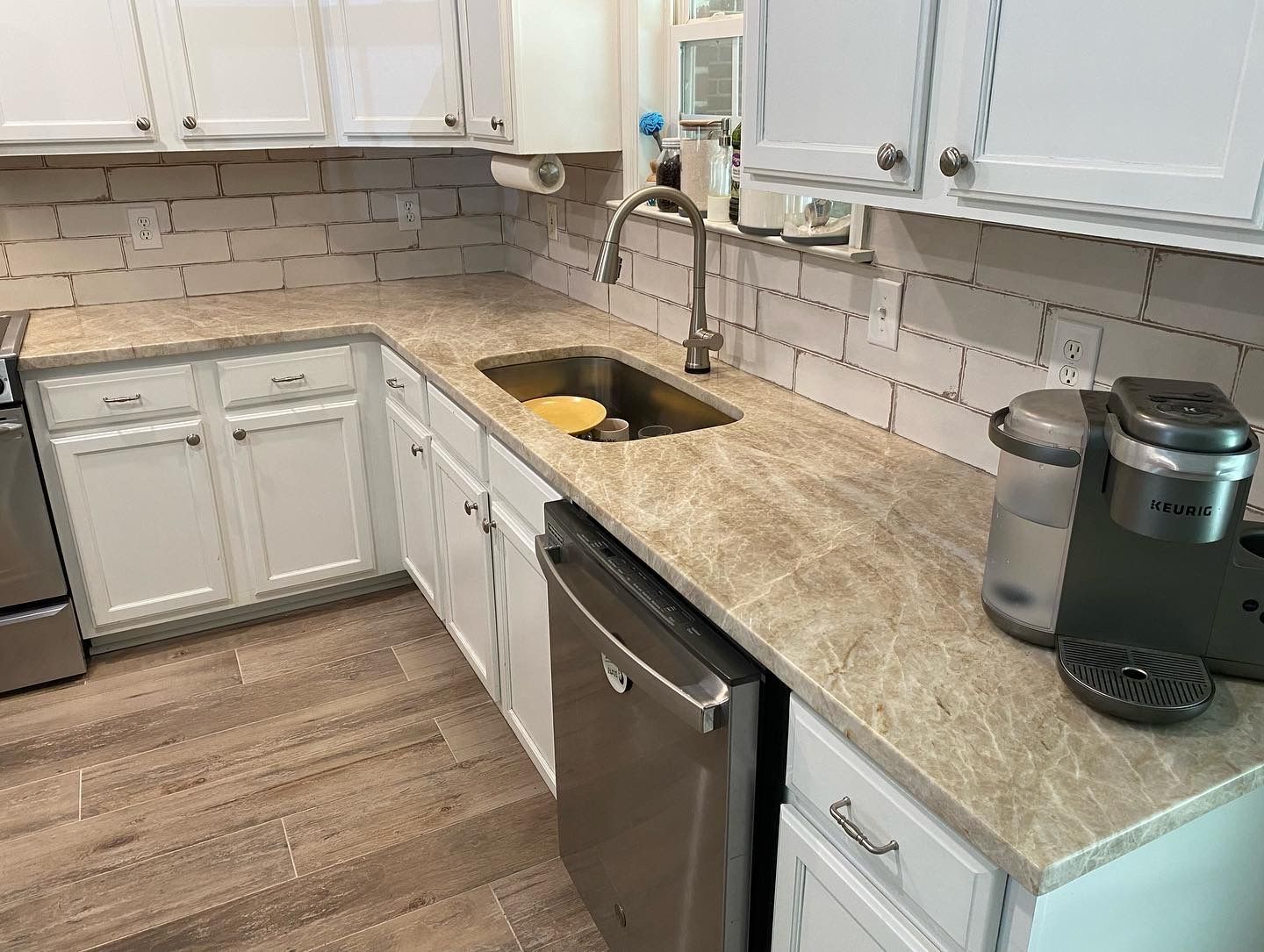 A kitchen with white cabinets , a sink , a dishwasher , and a coffee maker.