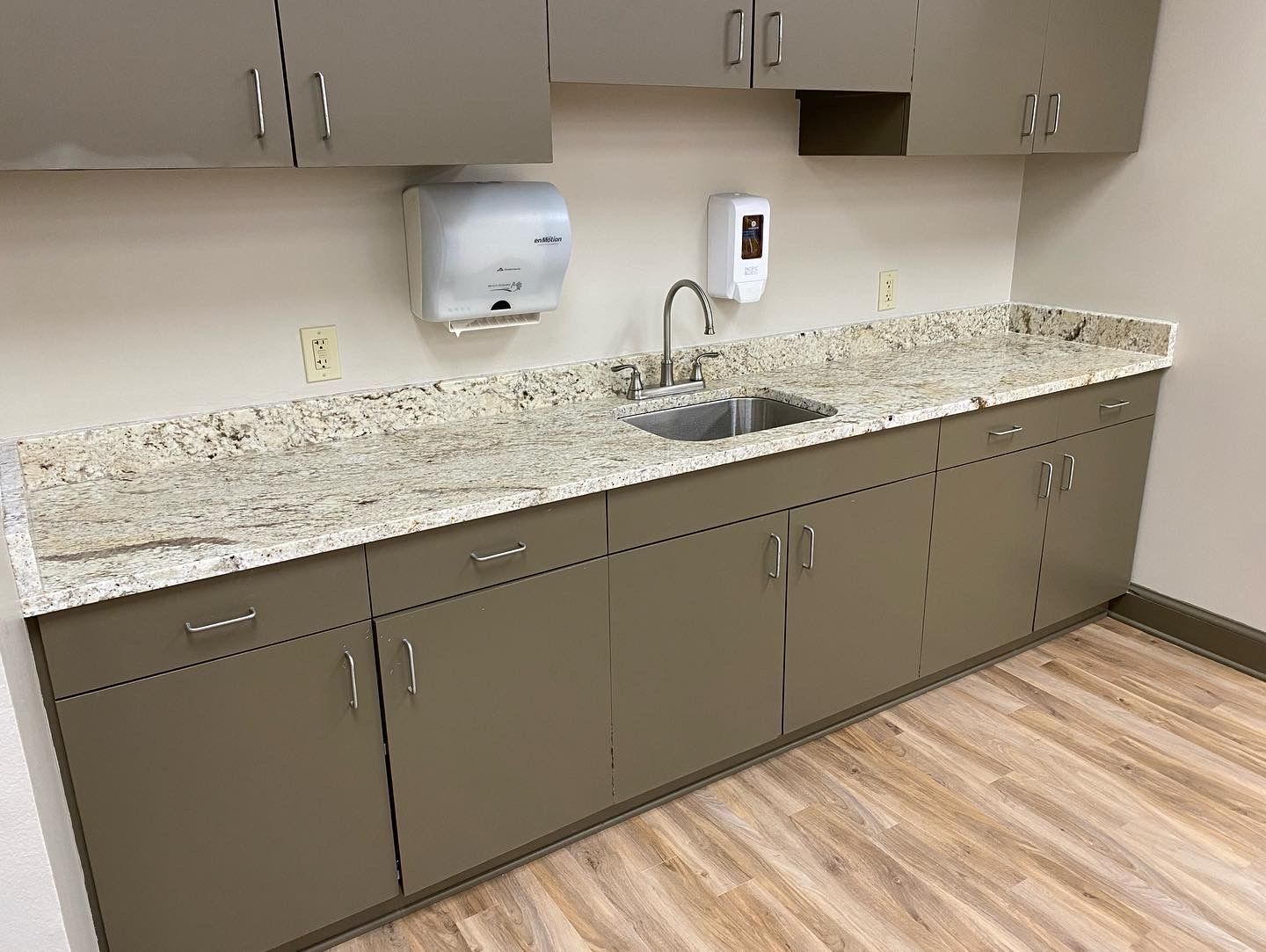 A kitchen with a sink , cabinets and granite counter tops.