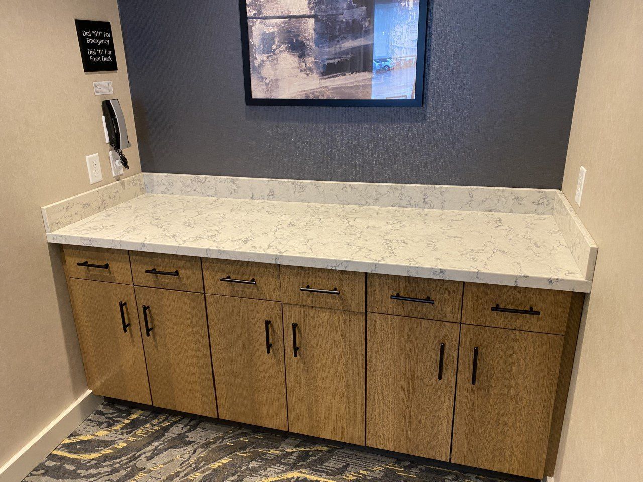 A kitchen counter with wooden cabinets and white counter tops.