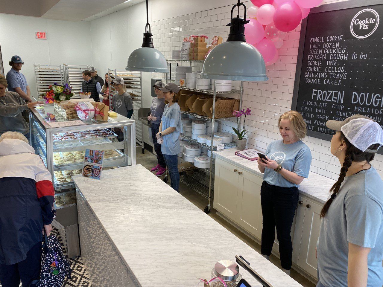 A group of people are standing around a counter in a bakery.