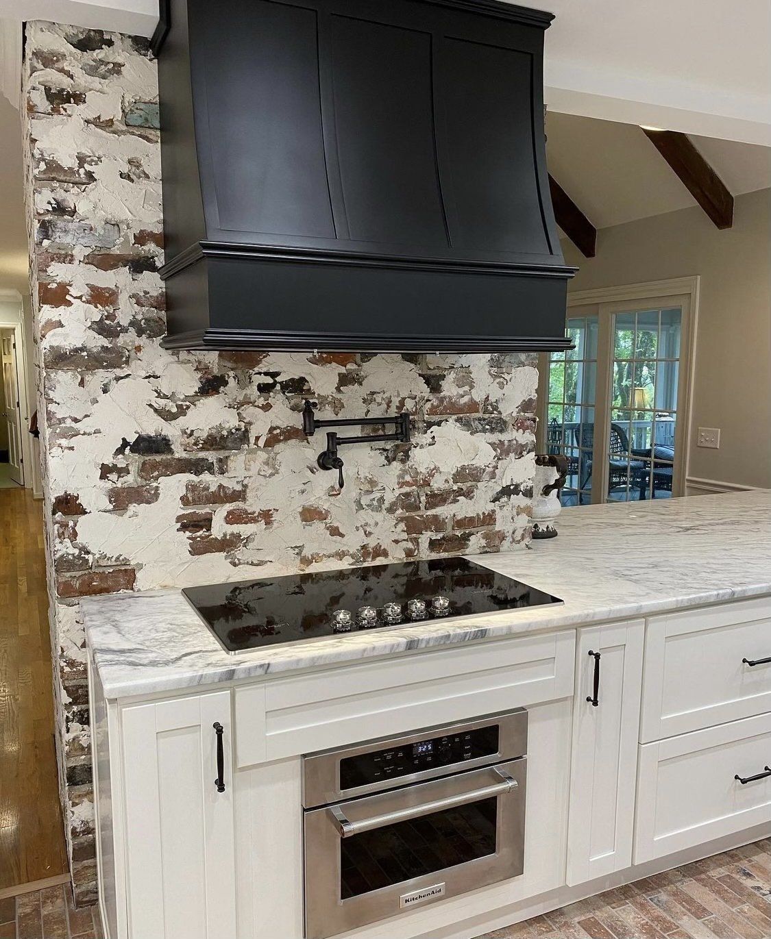A kitchen with white cabinets , a stove top oven , and a black hood.