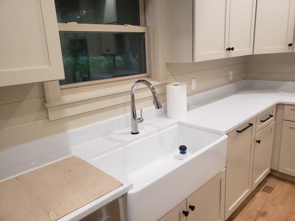 A kitchen with white cabinets and a white farmhouse sink.