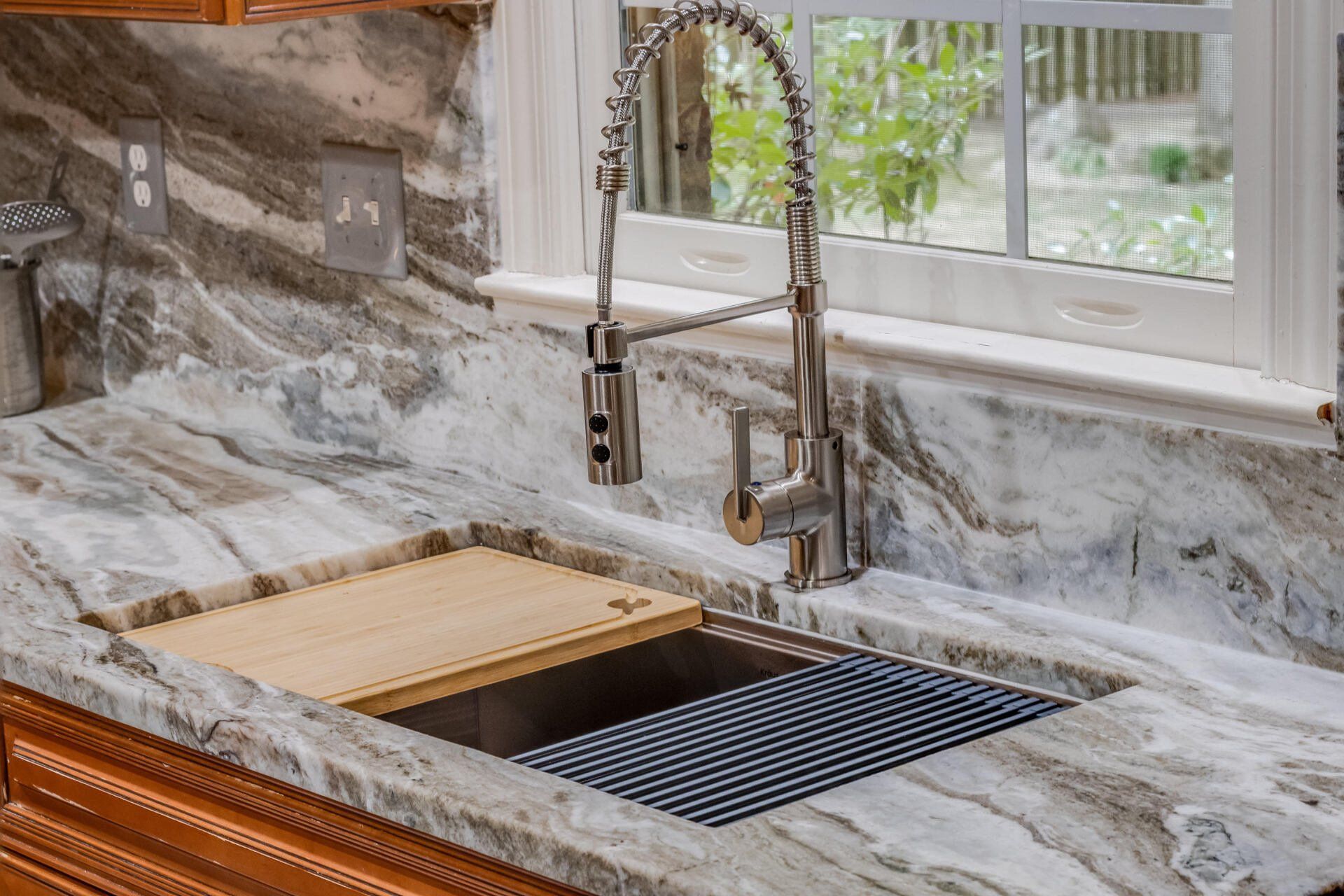 A kitchen sink with a faucet and a window in the background.