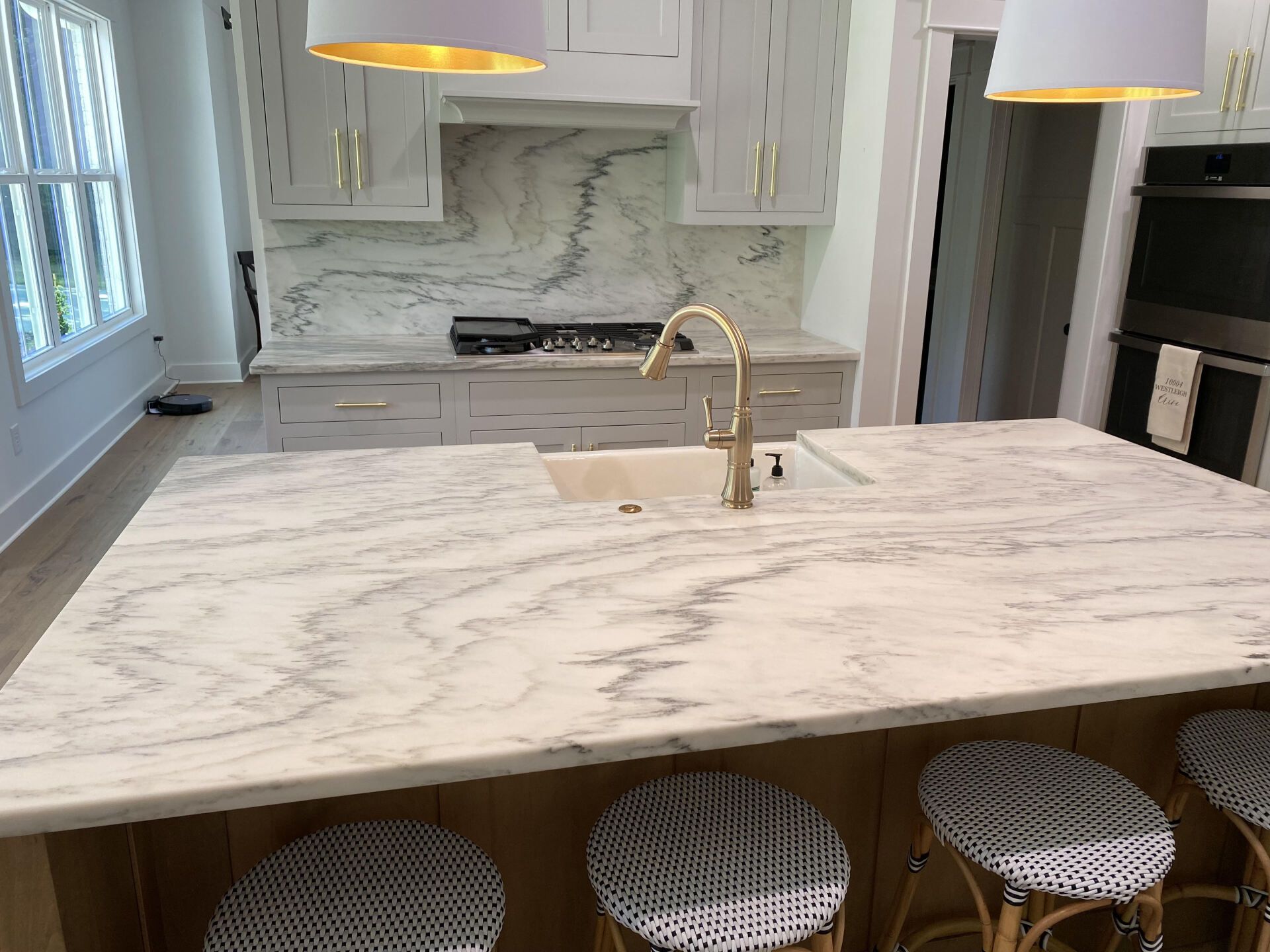 A kitchen with a large island , sink , and stools.